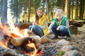 Cute little sisters roasting hotdogs on sticks at bonfire. Children having fun at camp fire. Camping with kids in fall forest. Royalty Free Stock Photo