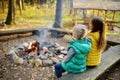 Cute little sisters roasting hotdogs on sticks at bonfire. Children having fun at camp fire. Camping with kids in fall forest. Royalty Free Stock Photo