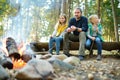 Cute little sisters and their father roasting marshmallows on sticks at bonfire. Children having fun at camp fire. Camping with ki