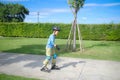 Cute little smiling Asian 7 years old child rollerblading in protection, helmet in sunny summer day