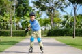 Cute little smiling Asian 7 years old child rollerblading in protection, helmet in sunny summer day Royalty Free Stock Photo