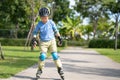 Cute little smiling Asian 7 years old child rollerblading in protection, helmet in sunny summer day Royalty Free Stock Photo