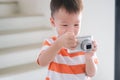 Cute little smiling Asian 2 - 3 years old toddler boy child taking photo using digital camera Royalty Free Stock Photo