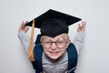 Cute little smiling blond boy in glasses wearing a student hat. Children education concept. Elementary School