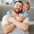 Cute little smiling caucasian boy hugging dad from behind at home. Carefree happy dad receiving love and affection from Royalty Free Stock Photo