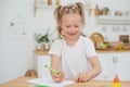 Cute little smiling girl enjoys studying and doing homework at home in the kitchen. Independent work Royalty Free Stock Photo