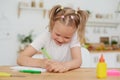 Cute little smiling girl enjoys studying and doing homework at home in the kitchen. Independent work Royalty Free Stock Photo