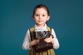 Cute little smiling girl photographer with old camera. Studio portrait on blue background Royalty Free Stock Photo