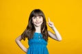 Cute little smiling girl raised her index finger up. An idea has come or points to a place for an inscription for a Royalty Free Stock Photo