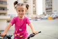Cute little smiling girl riding bike bicycle in city on parking sunny summer day. Active family leisure with kids Royalty Free Stock Photo