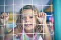 Cute little smiling girl sitting in protective fence .