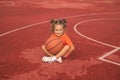 A cute little smiling girl is sitting in stadium with a basketball Royalty Free Stock Photo