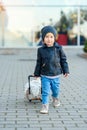 Cute little smiling girl in stylish clothes with pink suitcase in the airport. Kids travel. Royalty Free Stock Photo