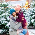 Cute little smiling kid girl and mother on christmas tree market. Happy child, daughter and woman in winter clothes Royalty Free Stock Photo