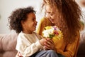 Cute little son giving flower bouquet his mom for Mothers day Royalty Free Stock Photo