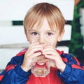 Cute little sporty boy drinks water. Kid outdoors. Child holds a glass of water. Kid with a glass of fresh water. Healthy and spor