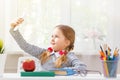 A cute little student girl is sitting at a desk with books. Child schoolgirl holds the phone and makes a selfie. Education. Royalty Free Stock Photo