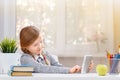 A cute little student girl is sitting at a table with a tablet. Education. Back to school. Sunlight from the window. Royalty Free Stock Photo