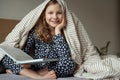 Cute teen child girl sitting and reading book on bed under the blanket Royalty Free Stock Photo