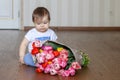 Cute little thoughtful baby boy sitting near the bunch of tulips Royalty Free Stock Photo