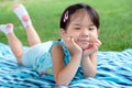 Little toddler girl laying on towel in the grass on a summer day Royalty Free Stock Photo