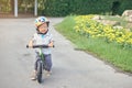 Cute little toddler boy child wearing safety helmet learning to ride first balance bike in sunny summer day, kid cycling at park Royalty Free Stock Photo