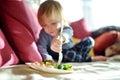 Cute little toddler boy eating broccoli. First solid foods. Fresh organic vegetables for infants Royalty Free Stock Photo