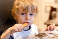 Cute little toddler boy peels fresh carrots. Adorable healthy kid eating vegetable snack. Happy child tasting healthy
