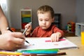 A cute little toddler boy of two years old with dad draws with markers in the album Royalty Free Stock Photo