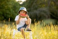 Cute little toddler child, blond boy, eating watermelon in beautiful daisy field