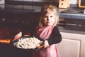 Cute little toddler girl baking apple pie at home. Happy smiling child helping with cake cake in domestic kitchen Royalty Free Stock Photo