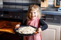 Cute little toddler girl baking apple pie at home. Happy smiling child helping with cake cake in domestic kitchen Royalty Free Stock Photo