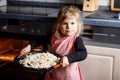 Cute little toddler girl baking apple pie at home. Happy smiling child helping with cake cake in domestic kitchen Royalty Free Stock Photo