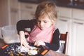 Cute little toddler girl baking plum pie at home. Happy smiling child helping and preparing plums for cake in domestic Royalty Free Stock Photo