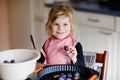 Cute little toddler girl baking plum pie at home. Happy smiling child helping and preparing plums for cake in domestic Royalty Free Stock Photo