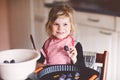 Cute little toddler girl baking plum pie at home. Happy smiling child helping and preparing plums for cake in domestic Royalty Free Stock Photo