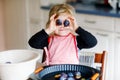 Cute little toddler girl baking plum pie at home. Happy smiling child helping and preparing plums for cake in domestic Royalty Free Stock Photo