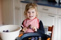 Cute little toddler girl baking plum pie at home. Happy smiling child helping and preparing plums for cake in domestic Royalty Free Stock Photo