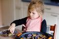 Cute little toddler girl baking plum pie at home. Happy smiling child helping and preparing plums for cake in domestic Royalty Free Stock Photo