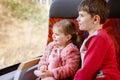 Cute little toddler girl and brother kid boy sitting in train and looking out of window. Two adorable happy healthy Royalty Free Stock Photo