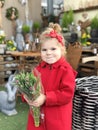 Cute little toddler girl with bunch of fresh tulips in flower shop. Adorable child in red coat buy flowers, tulips for Royalty Free Stock Photo