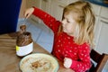 Cute little toddler girl eating homemade fresh crepes or pancakes with chocolate cream for breakfast. Royalty Free Stock Photo