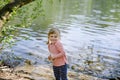 Cute little toddler girl feeding wild geese family in a forest park. Happy child having fun with observing birds and Royalty Free Stock Photo