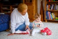 Cute little toddler girl and grandmother playing with toys at home. Adorable baby child and senior retired woman