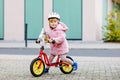 Cute little toddler girl with helmet riding on run balance bike to daycare, playschool or kindergarden. Happy child Royalty Free Stock Photo