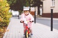 Cute little toddler girl with helmet riding on run balance bike to daycare, playschool or kindergarden. Happy child Royalty Free Stock Photo