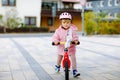 Cute little toddler girl with helmet riding on run balance bike to daycare, playschool or kindergarden. Happy child Royalty Free Stock Photo