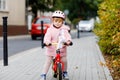 Cute little toddler girl with helmet riding on run balance bike to daycare, playschool or kindergarden. Happy child Royalty Free Stock Photo