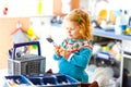 Cute little toddler girl helping in the kitchen with dish washing machine. Happy healthy blonde child sorting knives Royalty Free Stock Photo