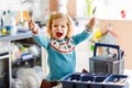 Cute little toddler girl helping in the kitchen with dish washing machine. Happy healthy blonde child sorting knives Royalty Free Stock Photo